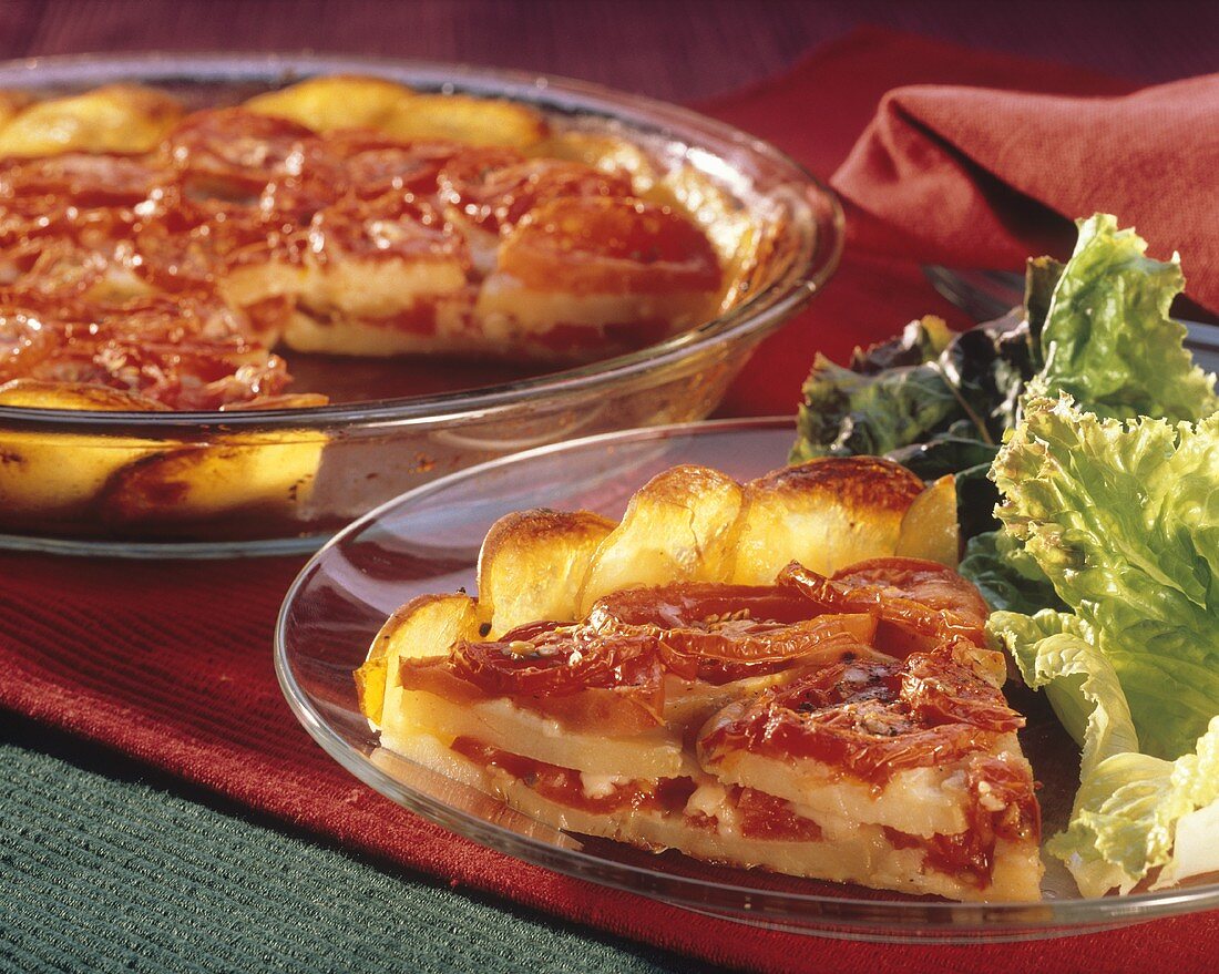 Tomaten-Kartoffelpie auf Teller mit Salat und in der Backform