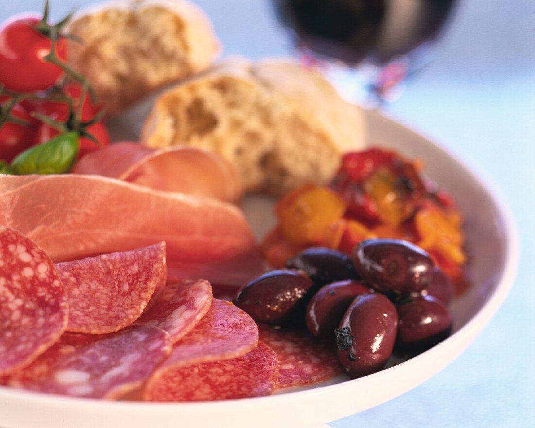 Sliced sausage and ham and pickled olives on plate