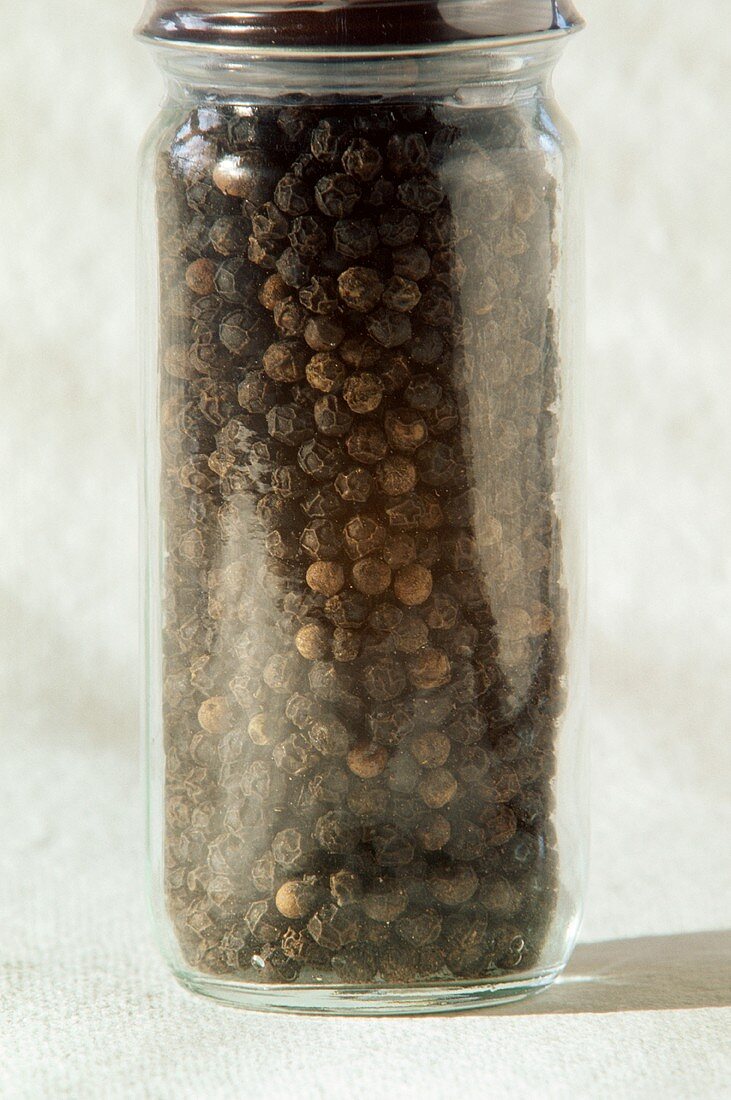 Schwarze Pfefferkörner in einem Glasbehälter