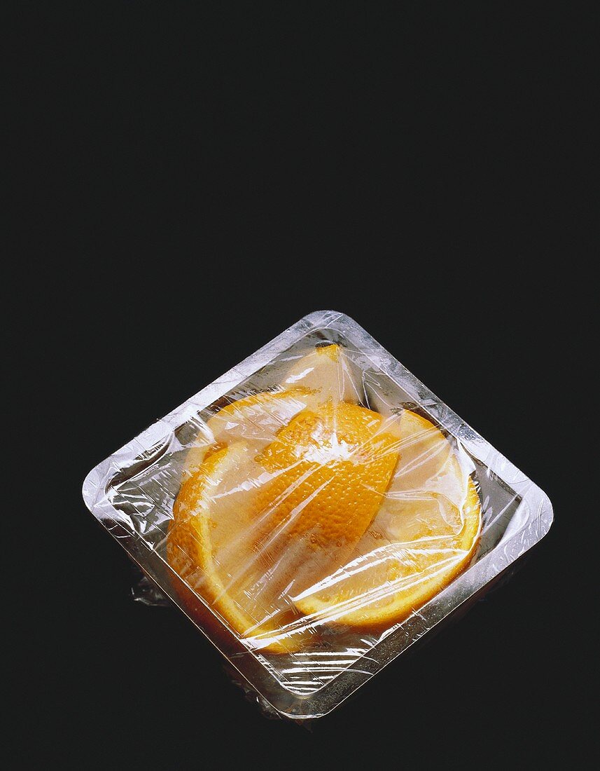 Orangenspalten in einem Plastikbehälter mit Plastikfolie