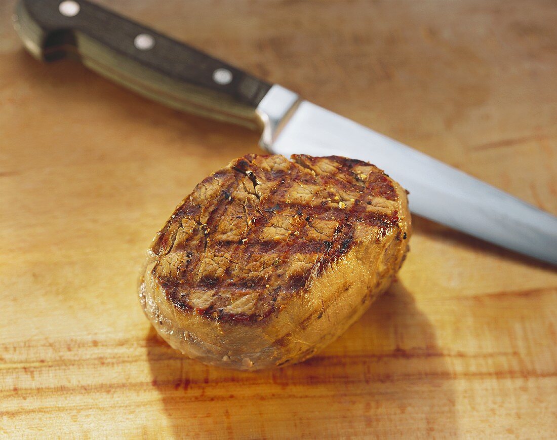 Gegrilltes Rinderfilet auf Holzuntergrund mit Messer