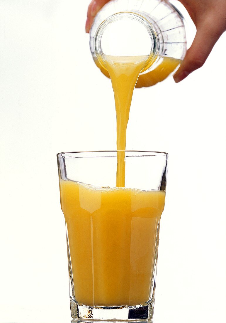 Orangensaft aus Flasche in Glas gießen