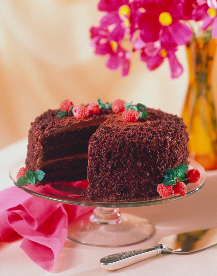 Schokoladentorte dekoriert mit Himbeeren auf Kuchenplatte