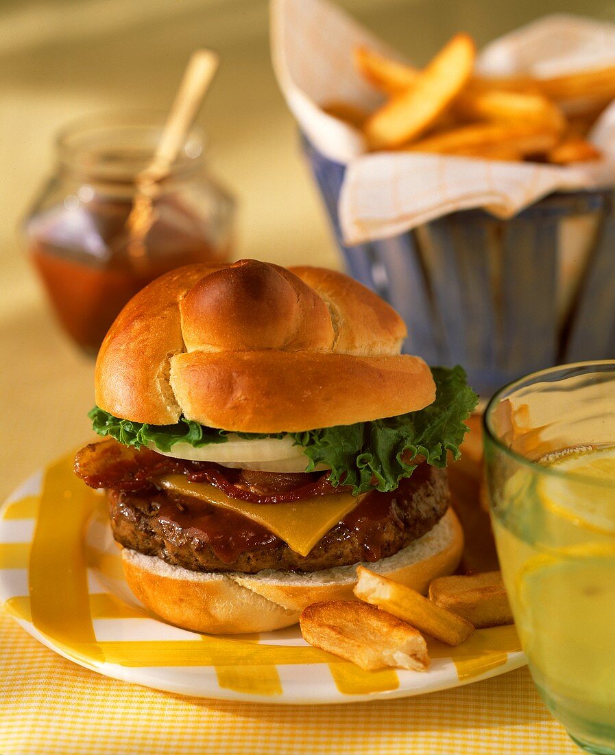 Cheeseburger mit Speck & Pommes frites auf Teller