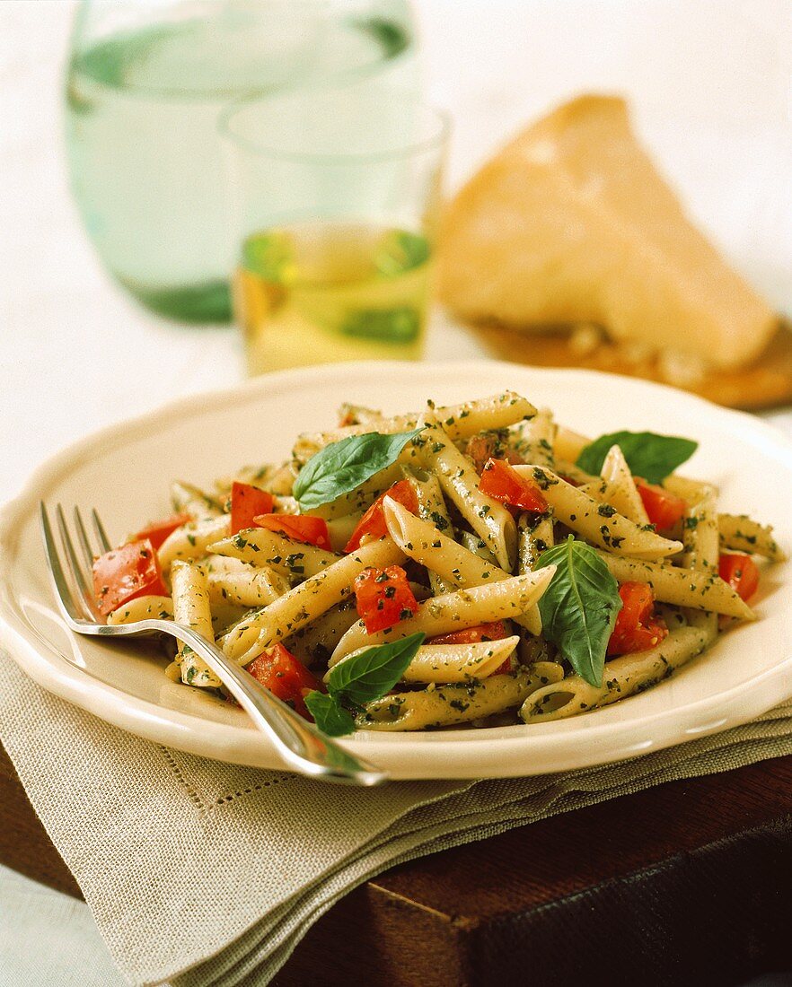 Penne mit Pesto, Tomaten & Basilikumblättchen auf Teller