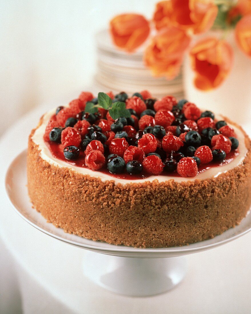 Ganzer Käsekuchen mit Beeren auf Kuchenplatte