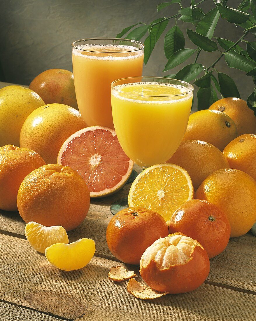 Orangensaft und Grapefruitsaft zwischen Orangen, Grapefruits