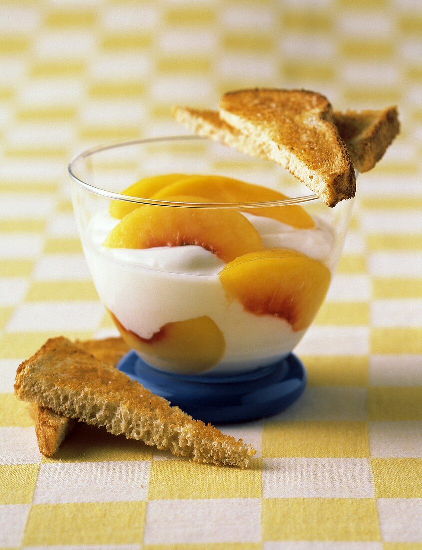 Joghurt im Glas mit Pfirsichspalten und Toast