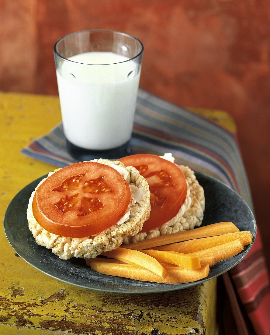 Reiswaffeln mit Tomatenscheiben und Möhrensticks; Milchglas