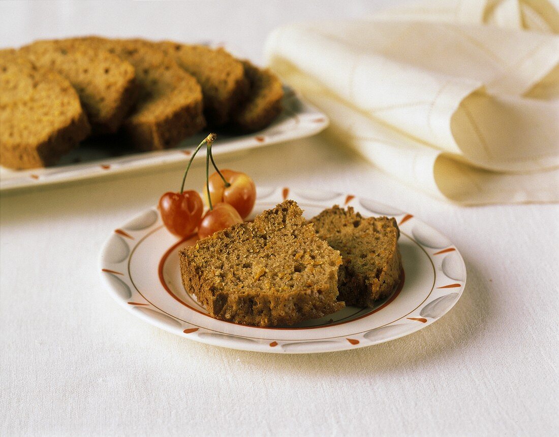 Möhrenbrot in Scheiben auf Teller mit Kirschen und Platte