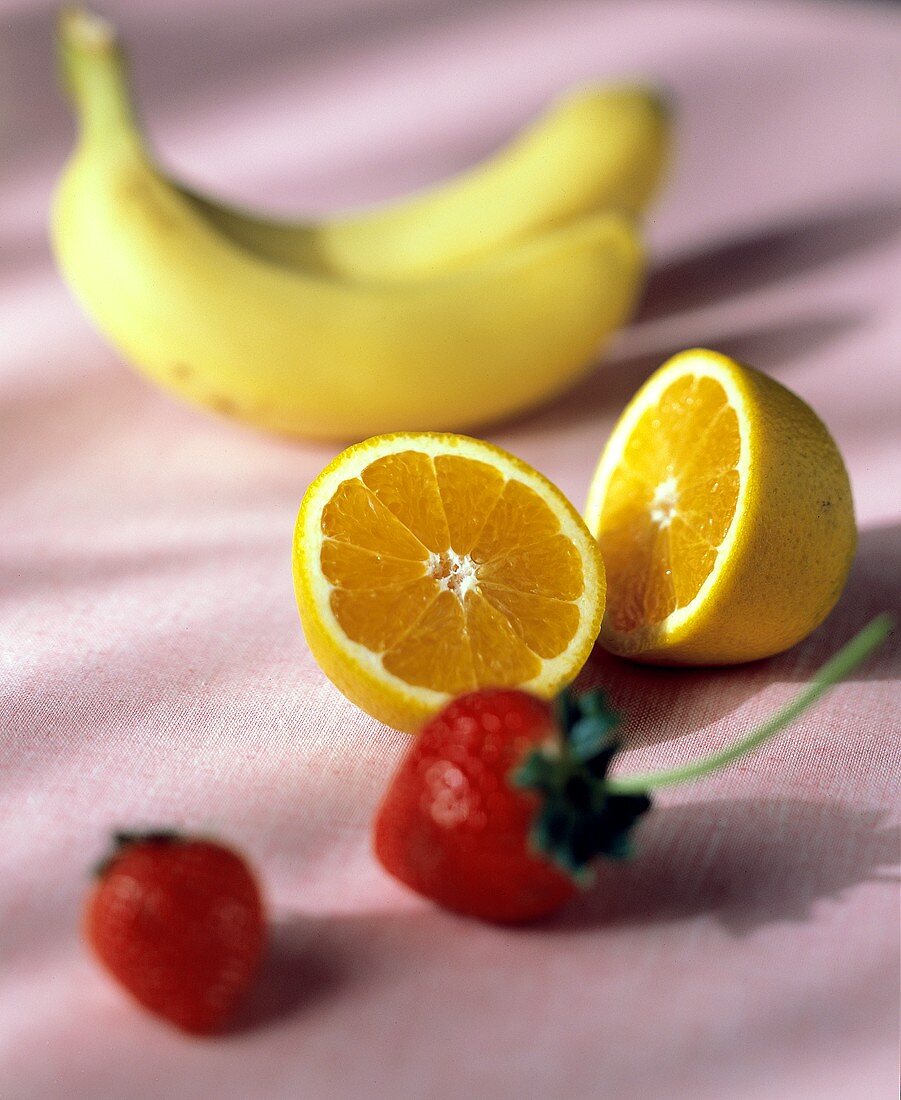 Stillleben mit Erdbeeren, halbierter Orange und zwei Bananen