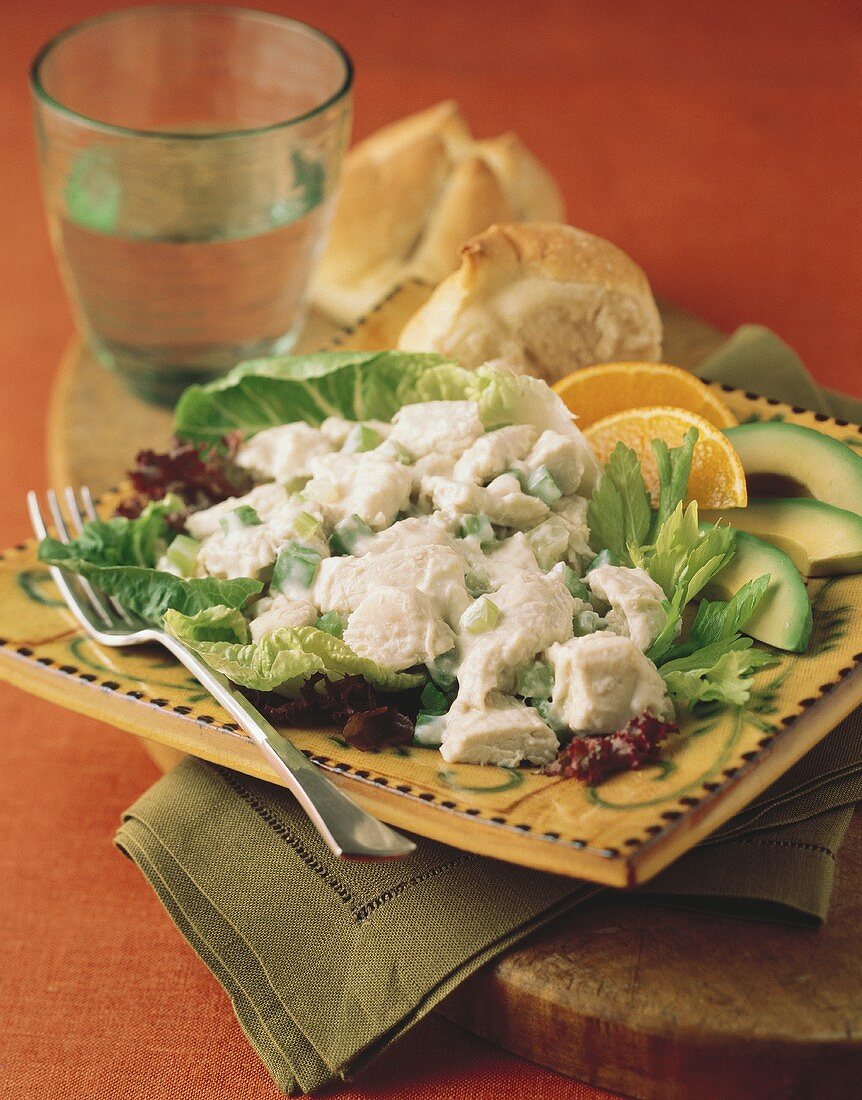 Hähnchensalat auf Salatblättern mit Avocadoscheiben, Orangen