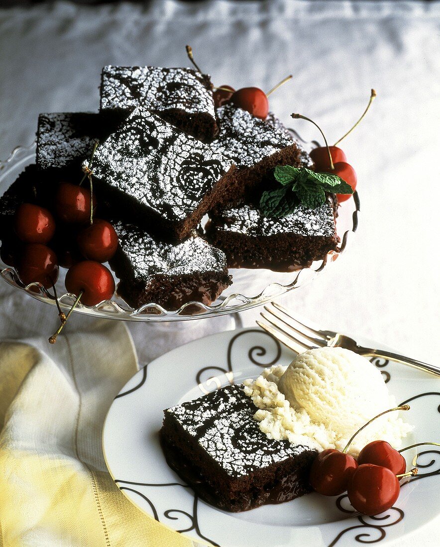 Viele Brownies auf Kuchenplatte & davor ein Brownie mit Eis