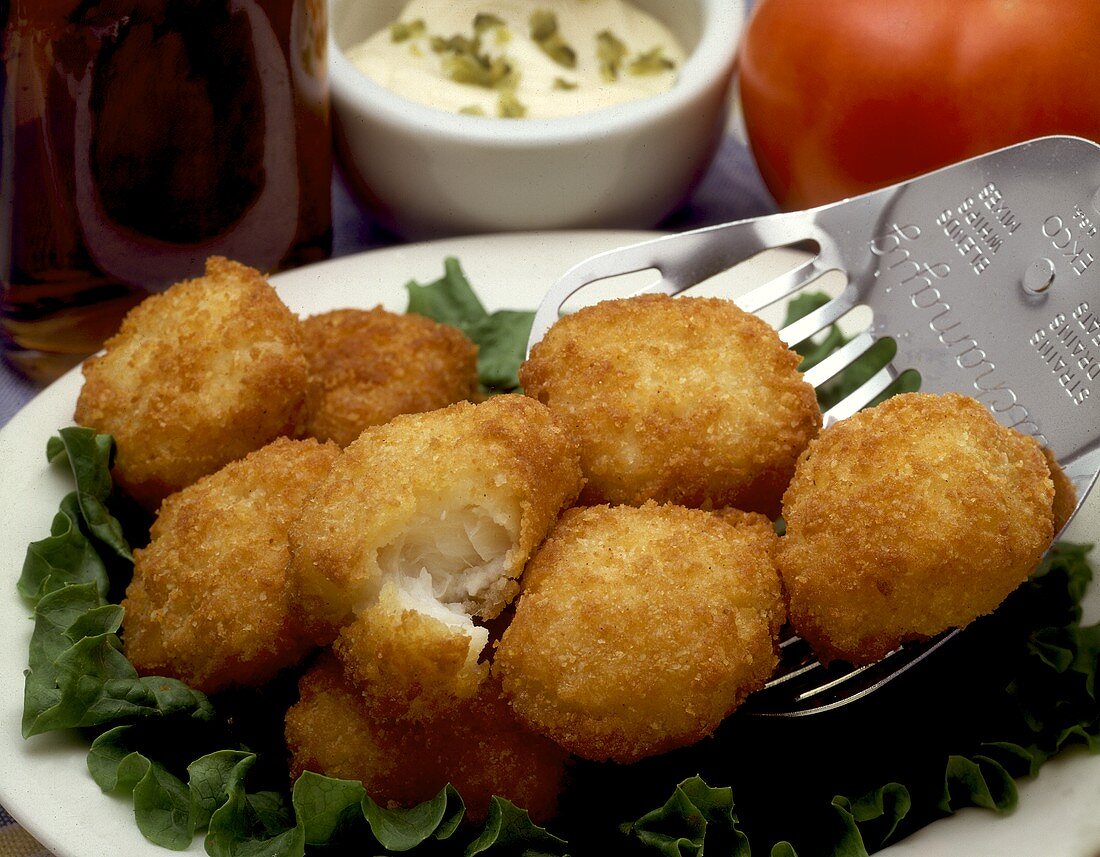 Frittierte Fischtaler auf Salatblättern und Pfannenwender