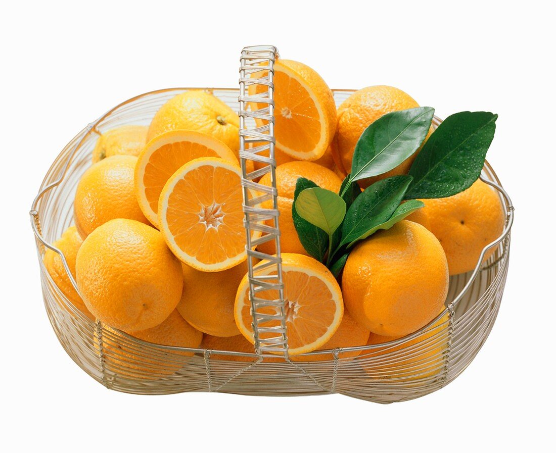 Ganze & halbierte Orangen in einem Drahtkorb
