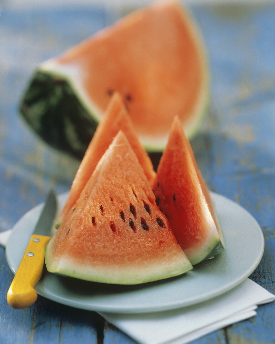 Wassermelonenschnitze mit Messer auf Dessertteller