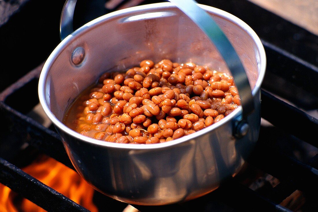 Bohneneintopf (Baked Beans) in einem Topf auf Campingfeuer