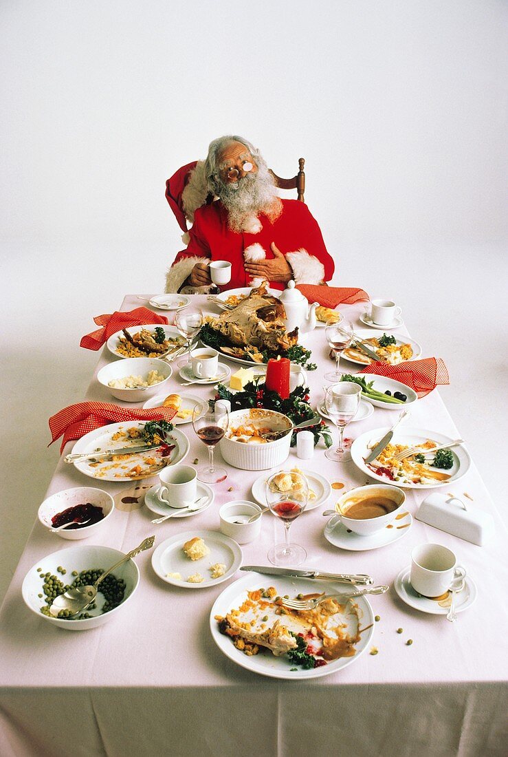 Weihnachtsmann sitzt am Tischende nach dem Weihnachtsessen