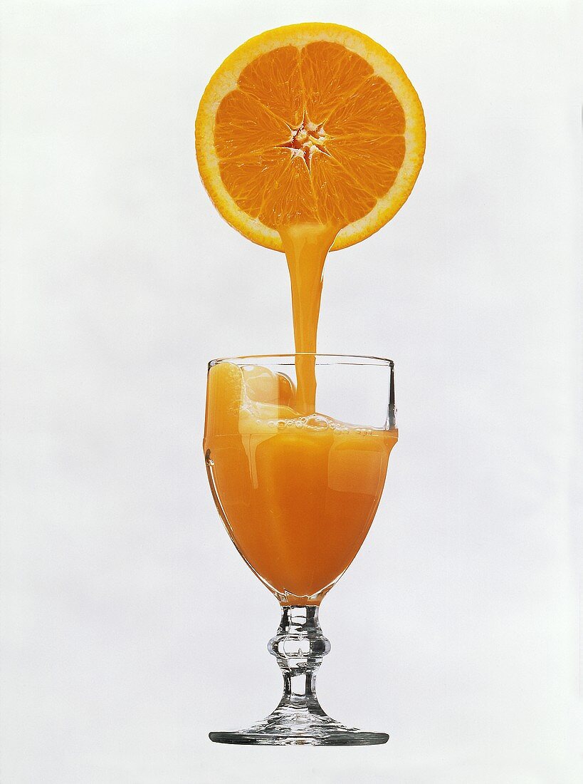 Orange Juice Pouring From an Orange into a Glass