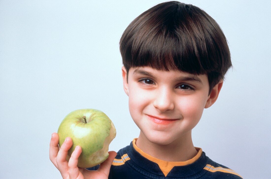 Kleiner Junge hält angebissenen Golden Delicious Apfel