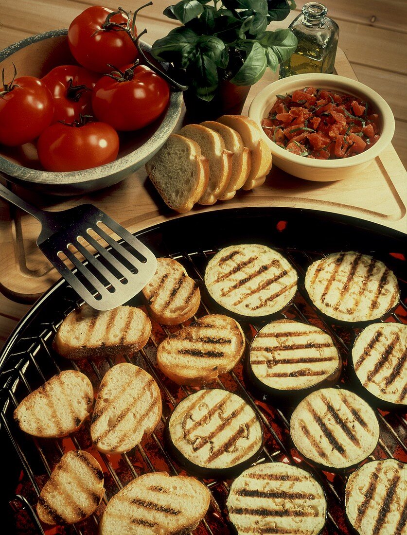 Gegrillte Auberginen und Brotscheiben auf dem Grill; Tomaten