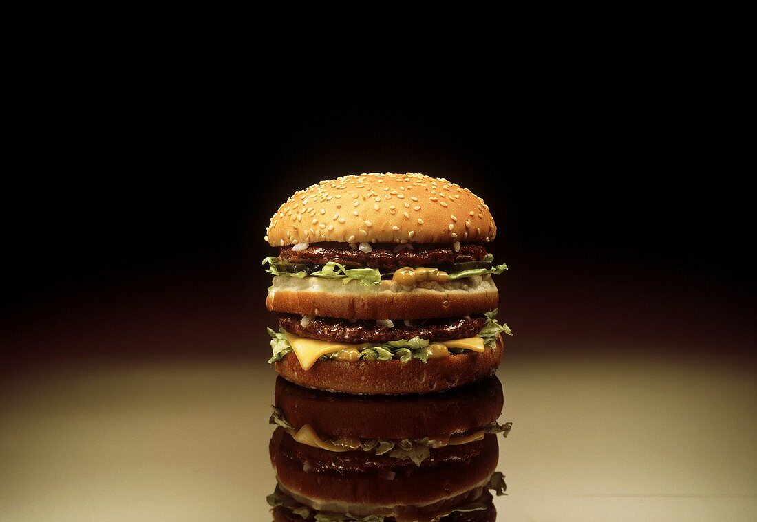 Ein doppelter Cheeseburger vor schwarzem Hintergrund