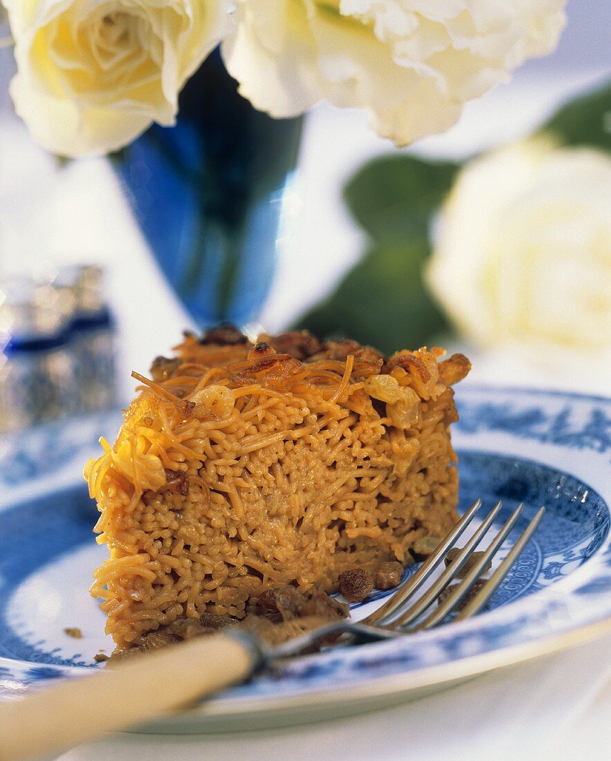 Ein Stück Kugel (jüdischer Nudelauflauf) auf Teller mit Gabel