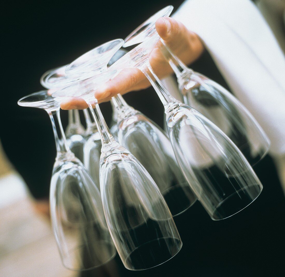 Hand Holding Several Empty Wine Glasses