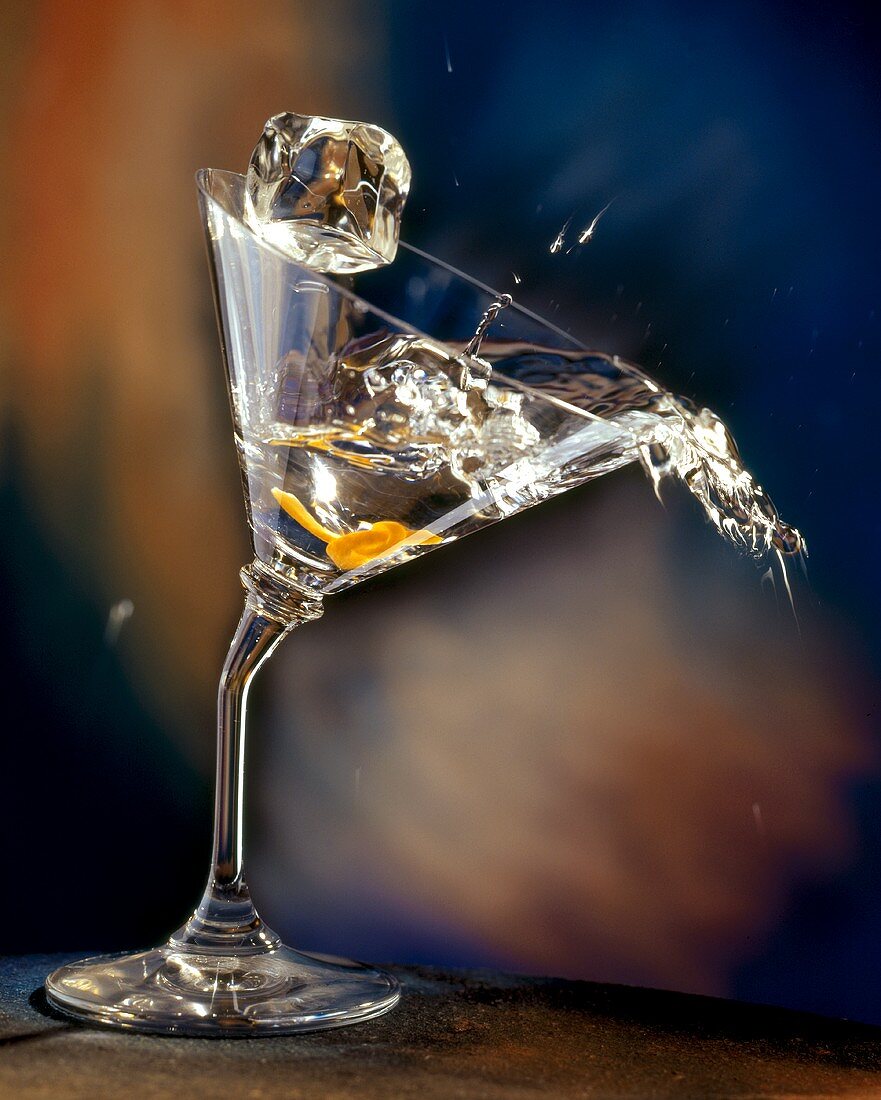 Vodka Martini Spilling From a Bent Martini Glass with Ice Cube