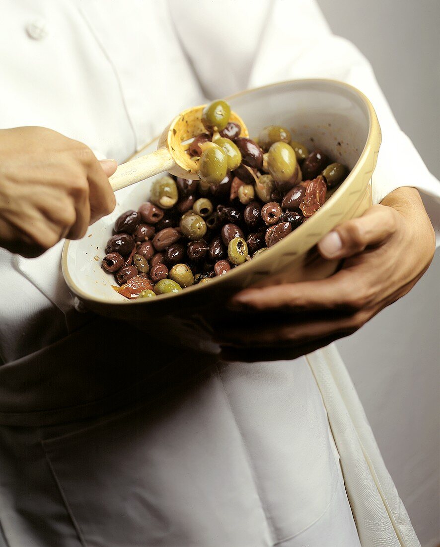 Chef Tossing Marinated Olives in a Bowl