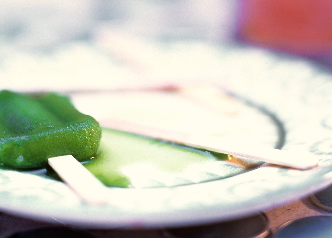 Geschmolzenes Limetteneis mit Stiel auf einem Teller