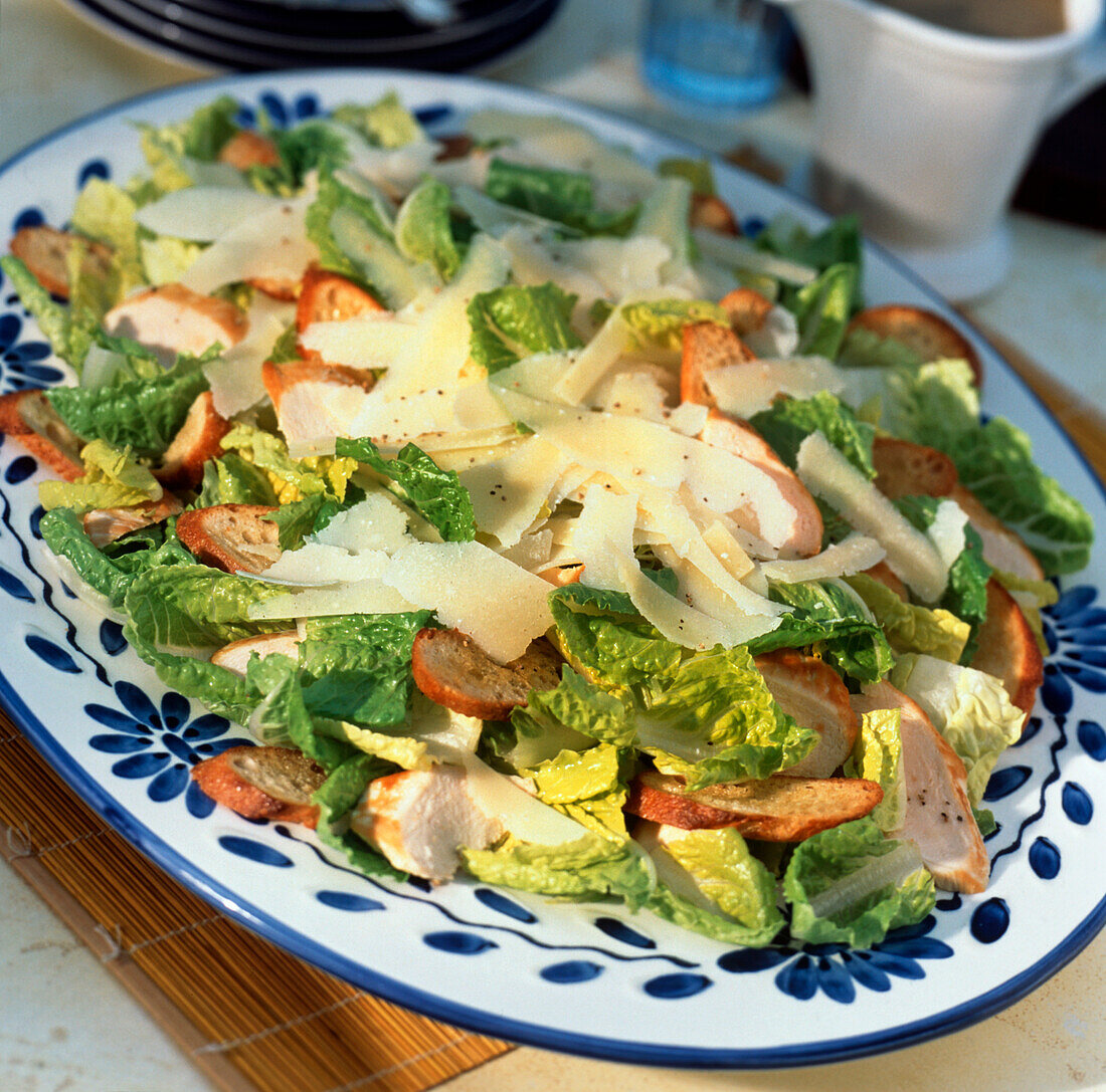 Cäsarsalat mit Parmesan auf blau-weißem Teller