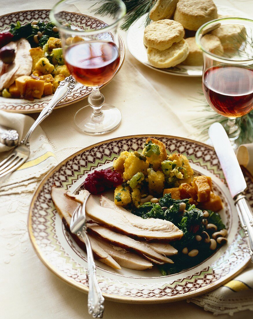 Holiday Dinner Plate with Turkey and Sides on Dinner Table with Wine and Biscuits
