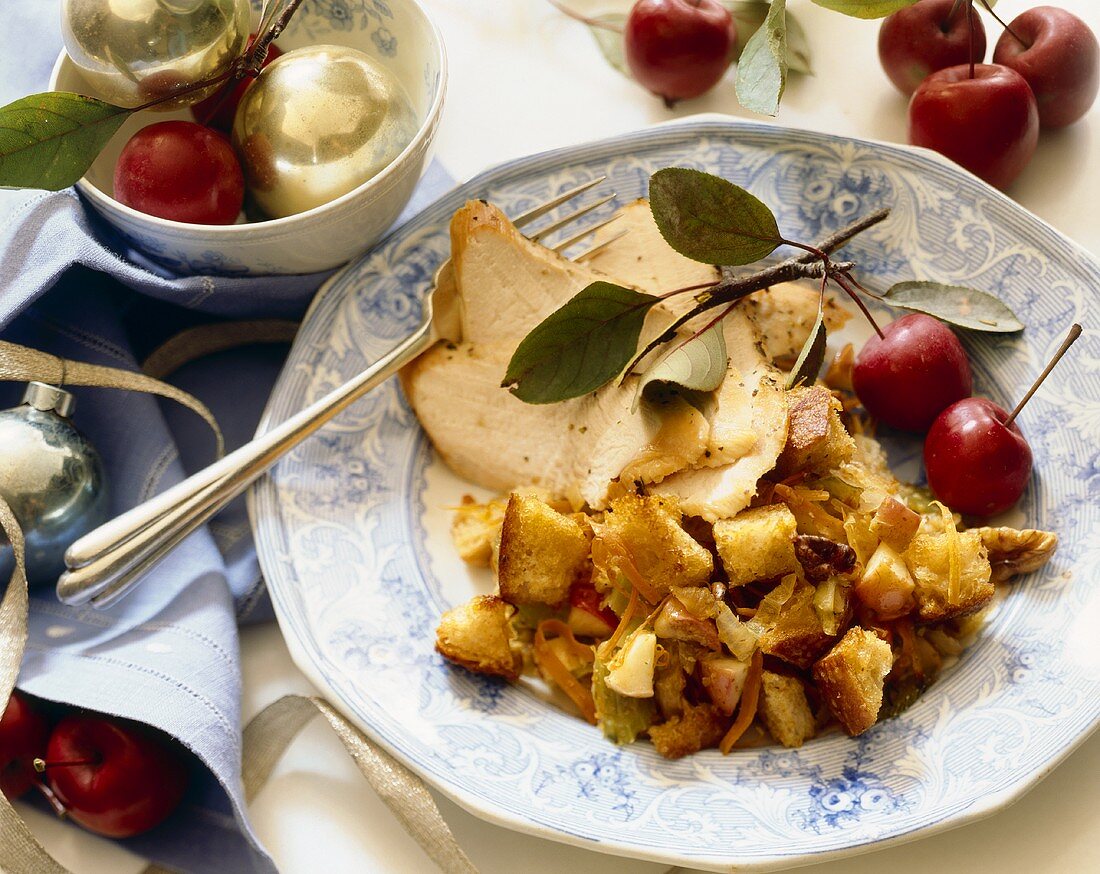 Two slices of roast turkey, bread stuffing and apples on a plate