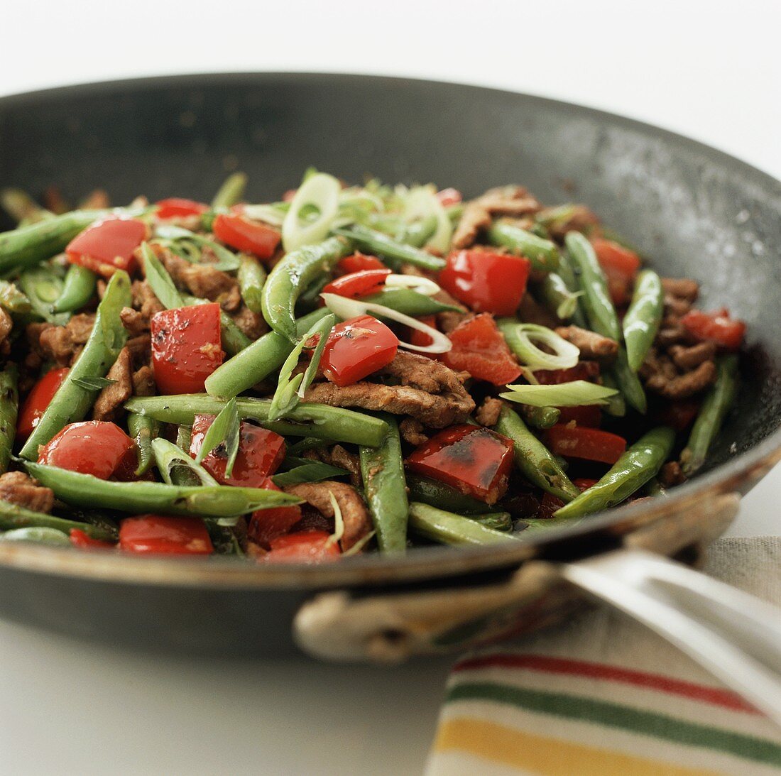 Strips of beef with peppers and green beans in frying pan