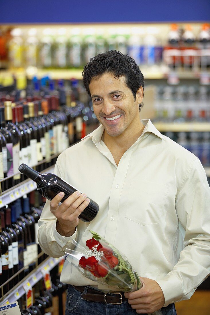 Mann mit Weinflasche und rotem Rosenstrauss im Supermarkt