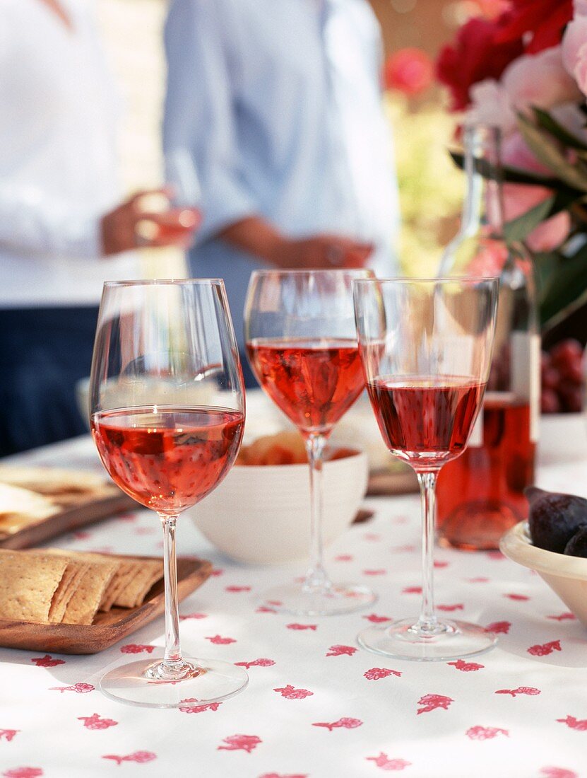 Glasses of rosé wine and assorted snacks on table