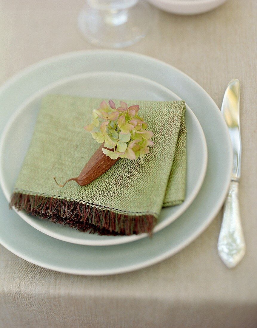 Place-setting with green fabric napkin & hydrangea flowers