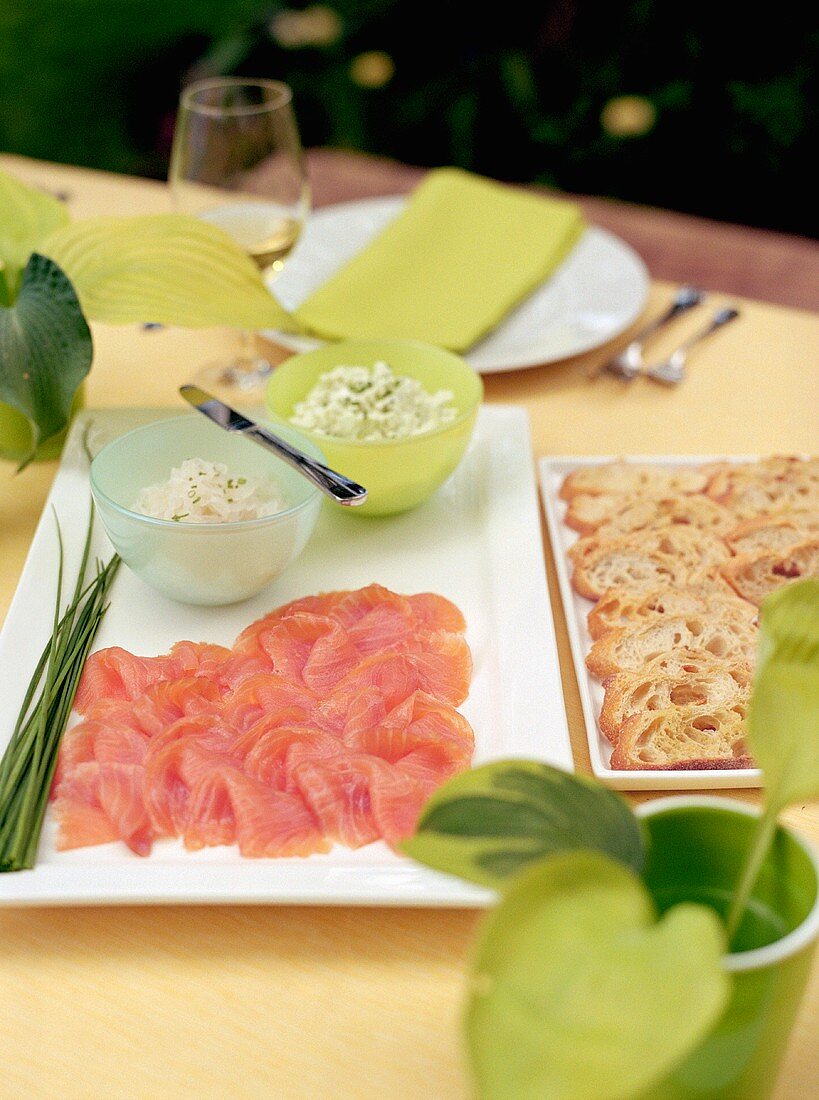 Smoked salmon, spreads and bread on table out of doors
