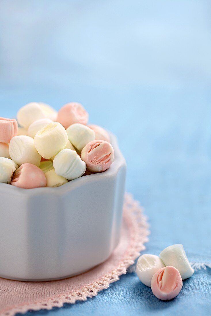 Pastel-coloured mint sweets in and beside white bowl