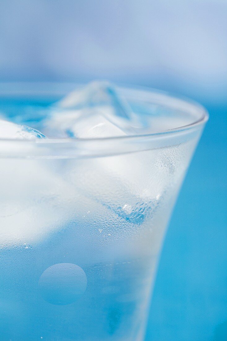 Glas Eiswasser vor blauem Hintergrund