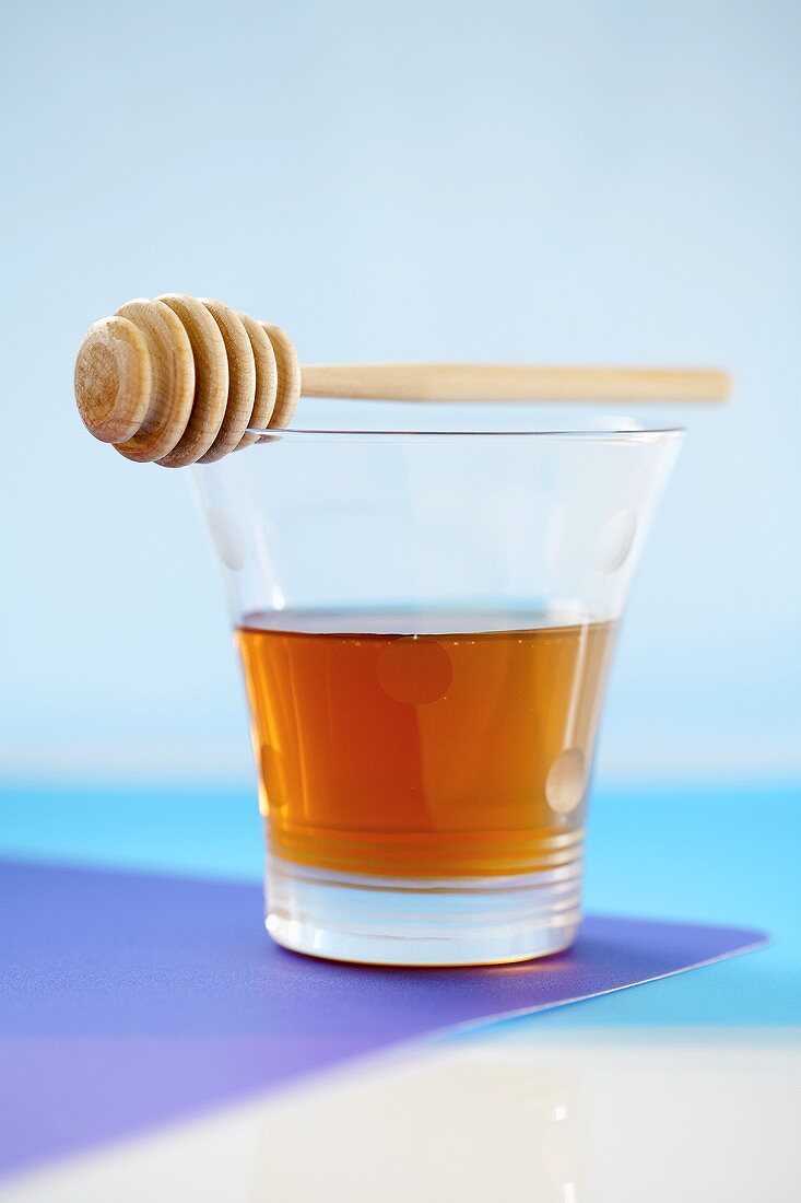 Glass of honey with honey dipper