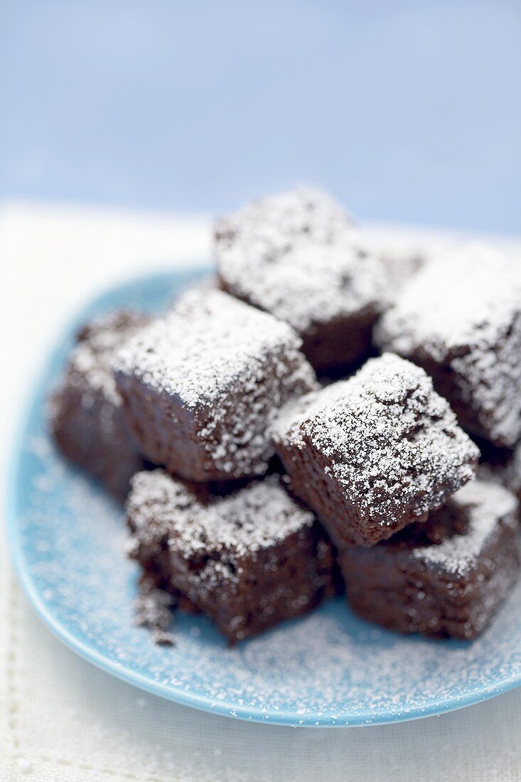 Small brownies with icing sugar on blue plate