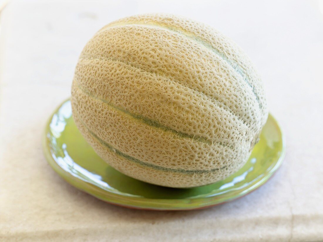 Whole cantaloupe melon on green plate