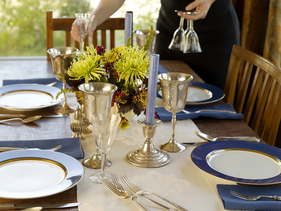 Hands Placing Glasses on a Set Table