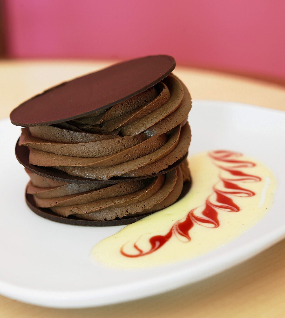 Layered chocolate mousse dessert with decorative cream sauce