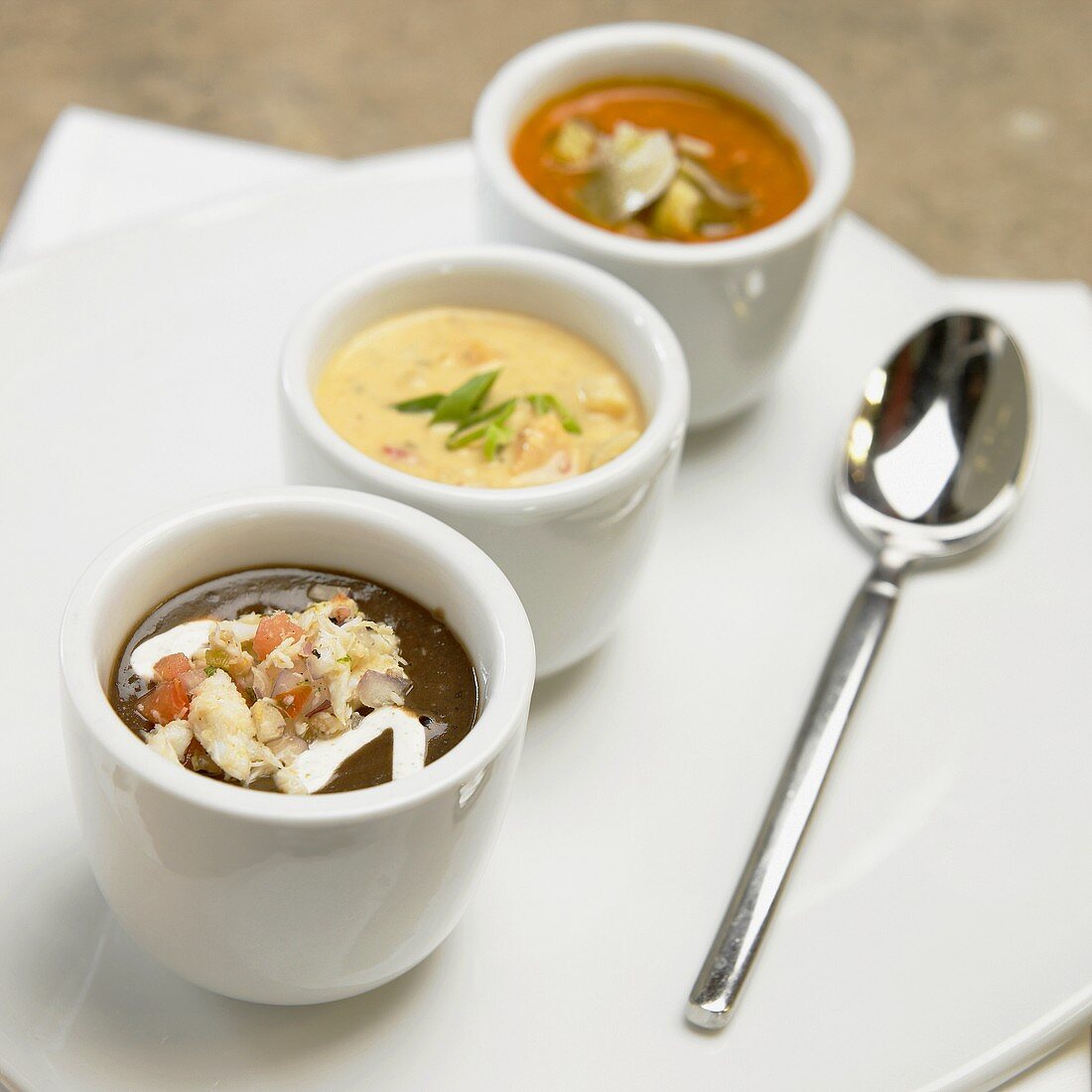 Three different soups in small bowls