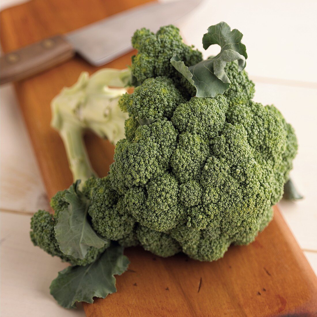 Fresh broccoli on chopping board, knife in background