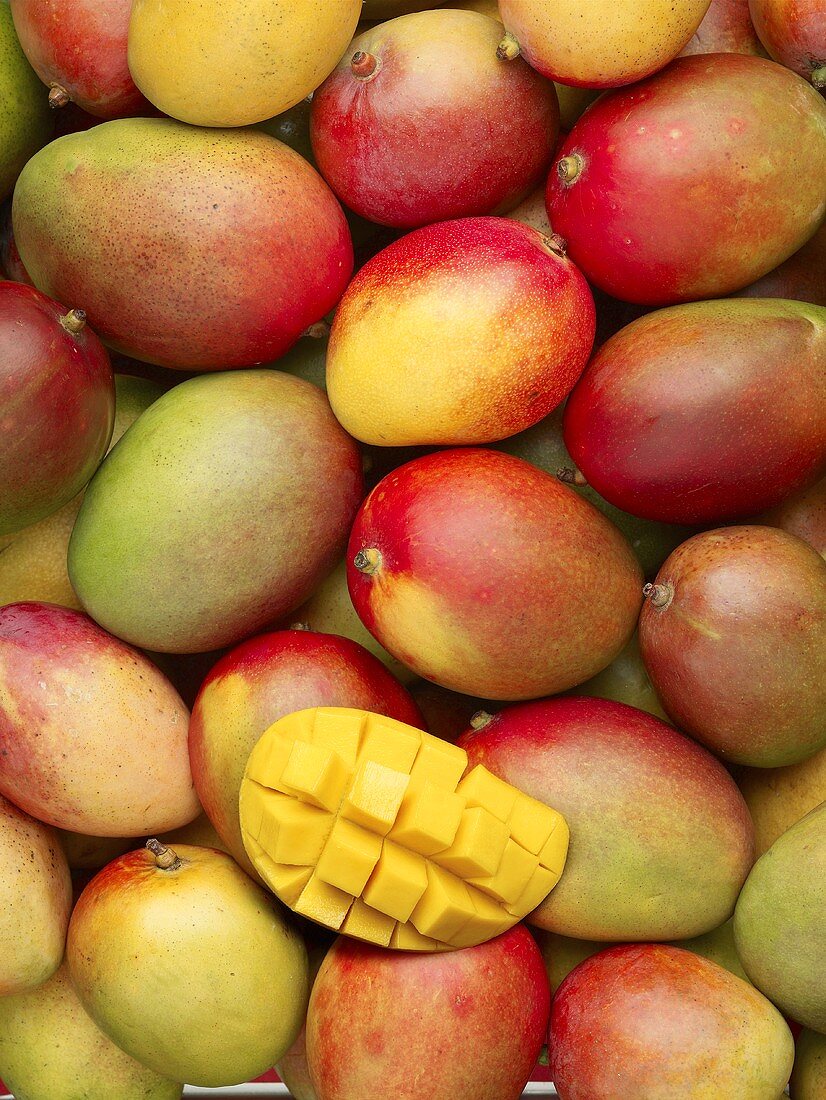 Viele ganze Mangos und eine aufgeschnittene (bildfüllend)