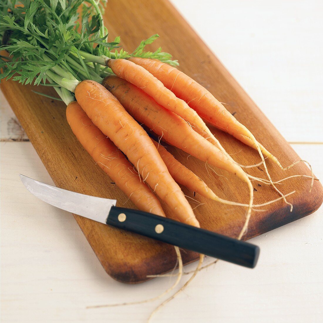 Fresh carrots on chopping board with knife